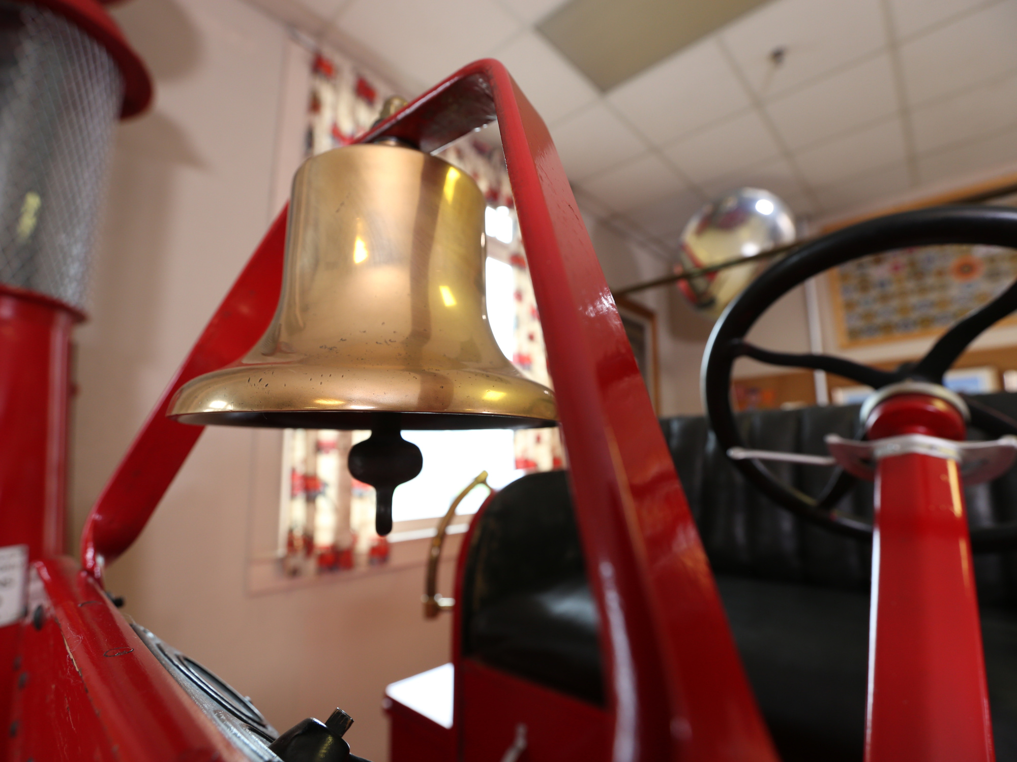 A close-up shot highlighting the details of a vintage fire truck, including a brass bell.